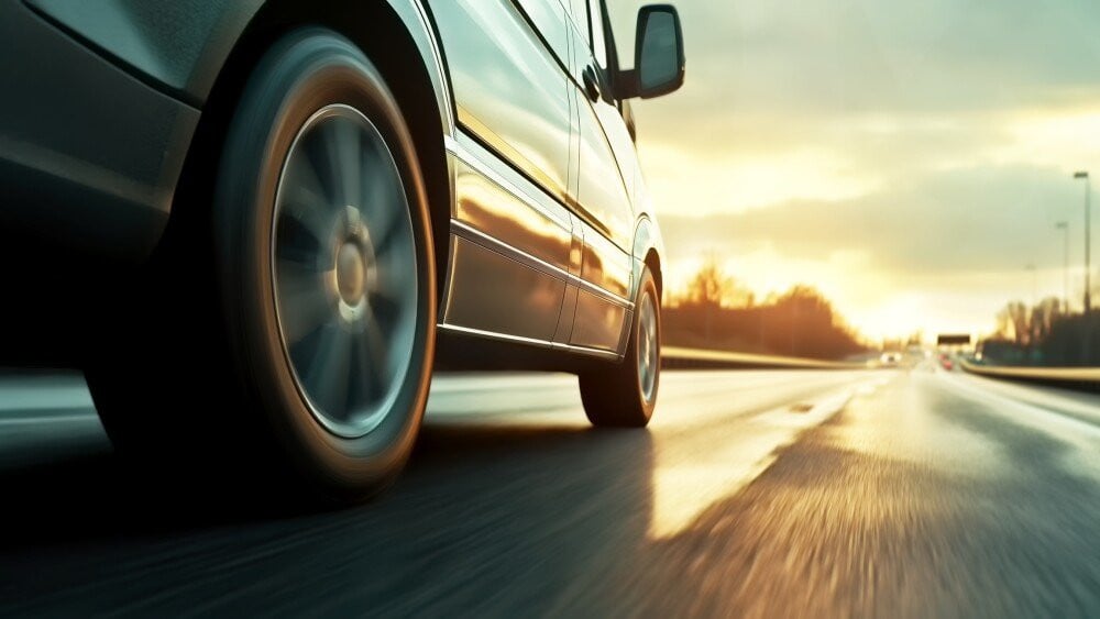 Low angle side view of car rushes along the highway at sunset