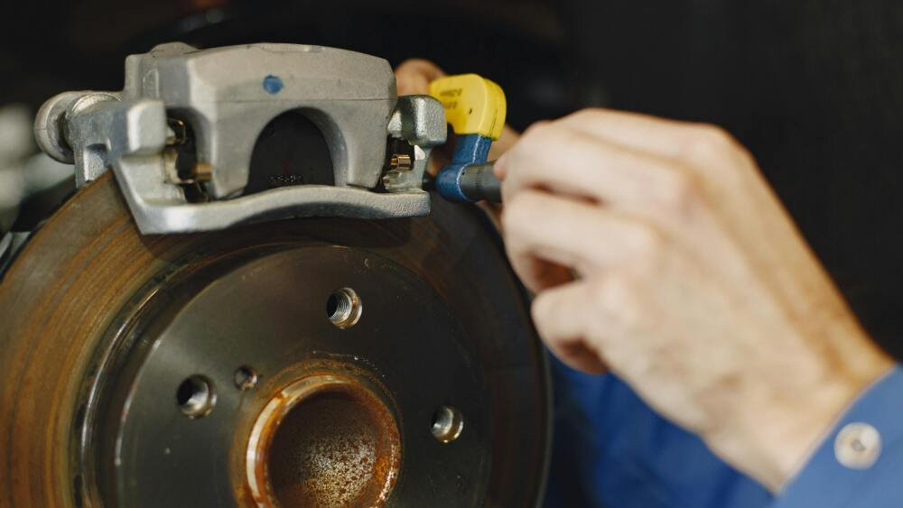 A technician measures a brake disc with a micrometer