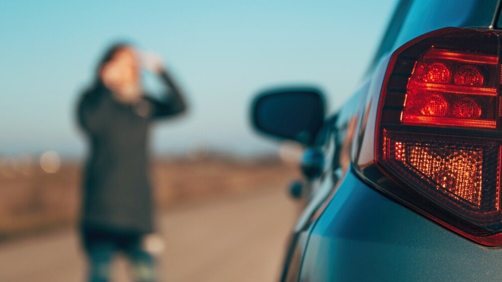 Woman making a phone call while standing by the broken down vehicle at the roadside calling road service and maintenance mechanics selective focus