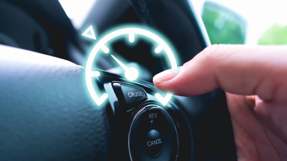 Automotive cruise control system on the steering wheel of the car with speedometer lock indicator and driver hand