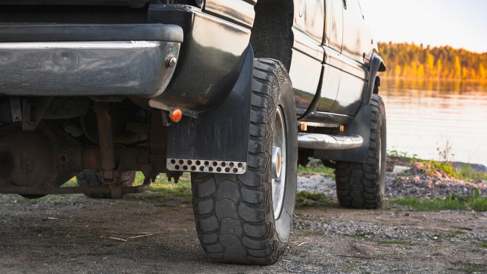 Black SUV car fragment. Still lake coast on a background