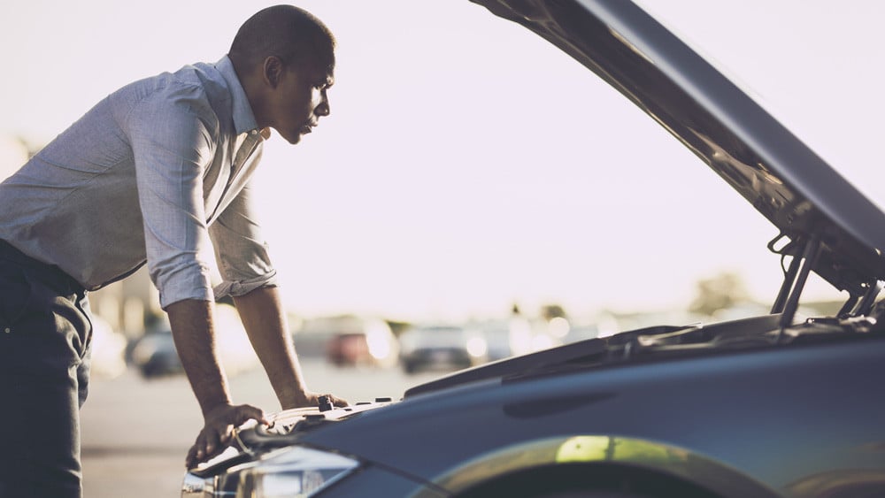 man checking under the hood after having car trouble