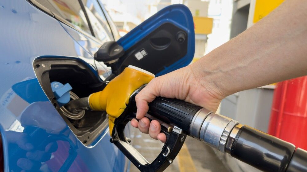 Man holds fuel nozzle into the gas tank of a car at the gas station