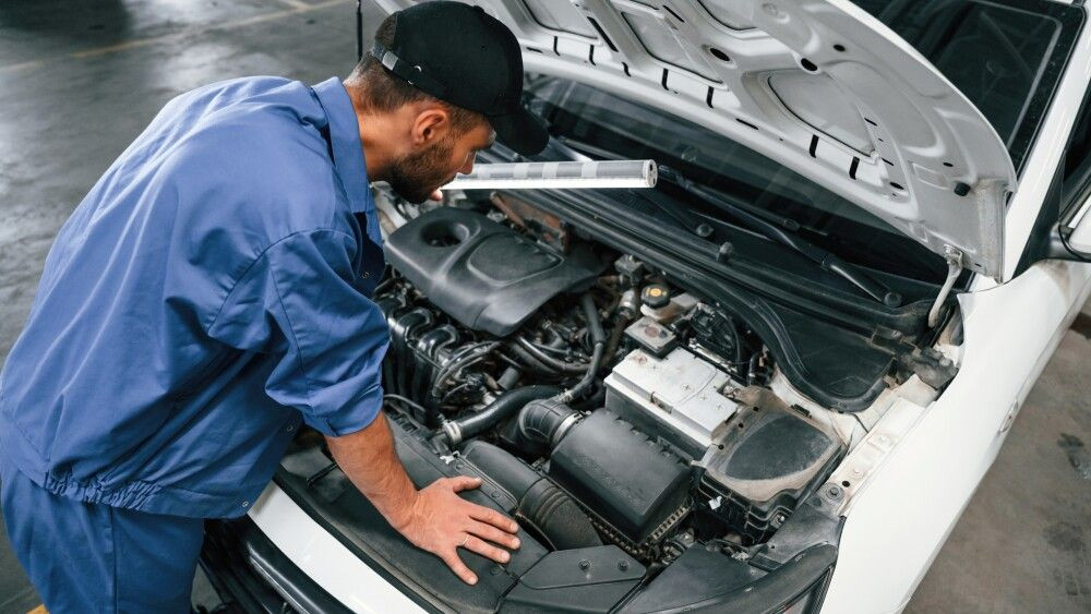 Top view. Hood is opened. Auto mechanic working in garage. Repair service.