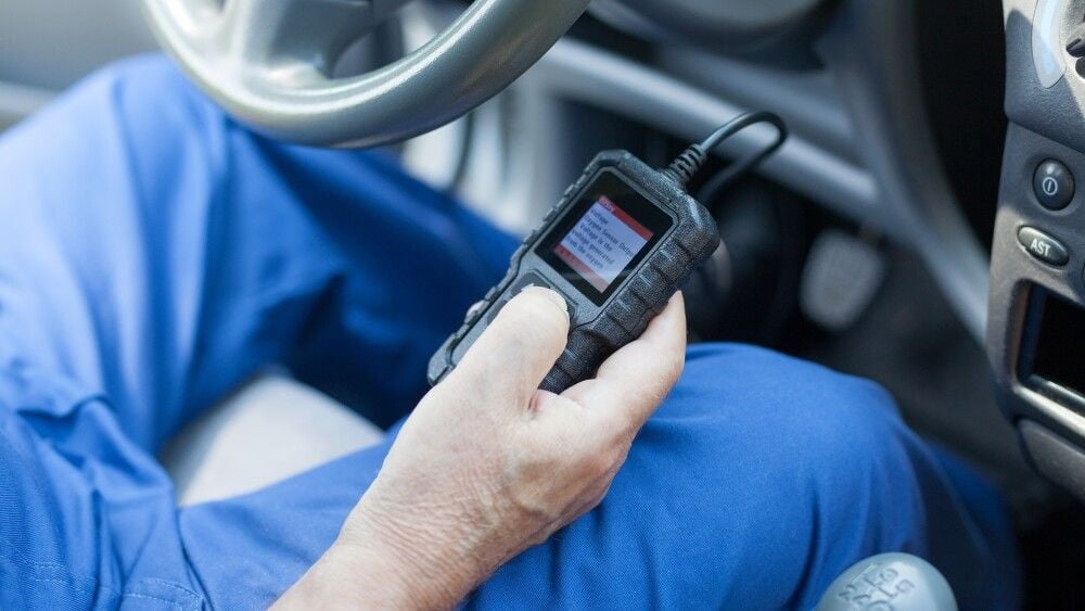 Auto mechanic using car diagnostic scanner tool