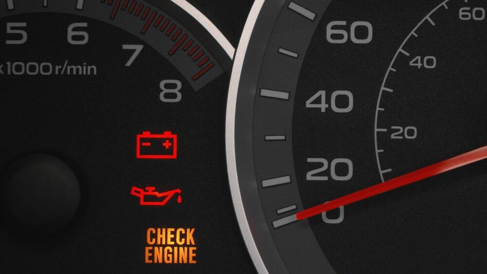 Close up on a cluster with the check engine warning light on indicating a car failure