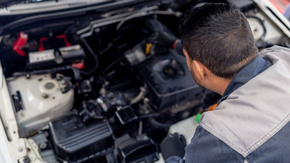 Mechanic checking the oil levels of a car under the hood at an Auto Repair Shop