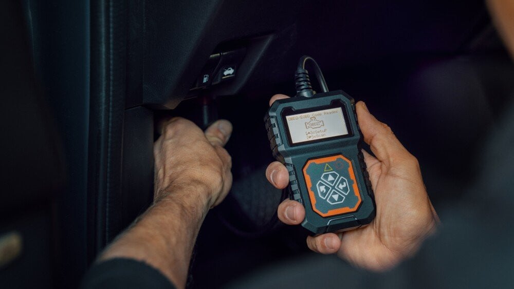car mechanic using OBD2 scanner, code reader tool to check engine errors and for diagnostics