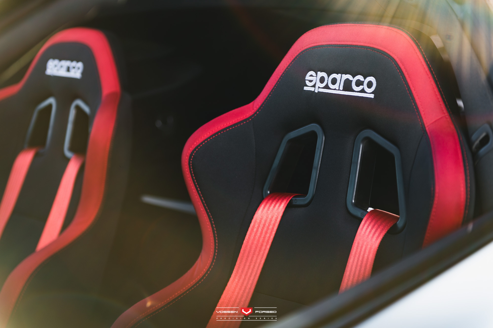 Black Sparco sport seats with red accents and seat belts - Photo by Vossen